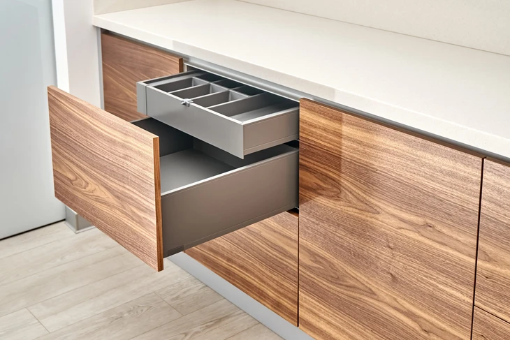 Une main ouvre délicatement une porte d'armoire de cuisine moderne dans un environnement domestique contemporain