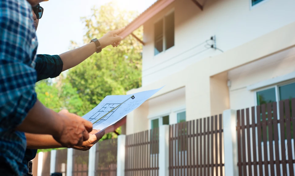 Installateur professionnel en casquette effectuant la pose d'une fenêtre PVC blanche à double vitrage dans un intérieur résidentiel