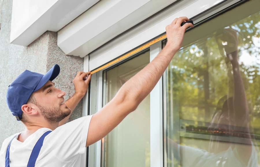 Le travailleur installe et vérifie la fenêtre dans la maison