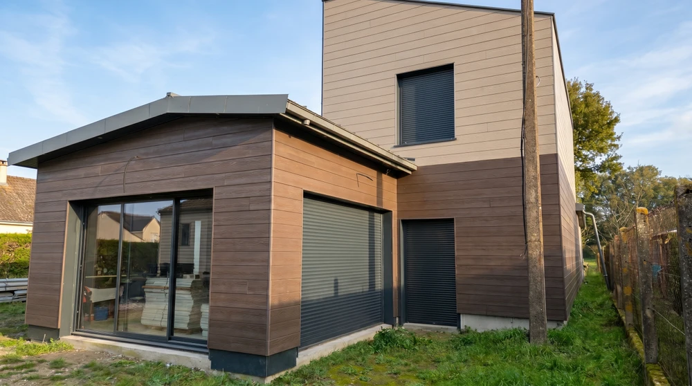 Maison neuve à ossature bois avec bardage horizontal en sapin naturel, toiture en ardoise avec chéneau zinc