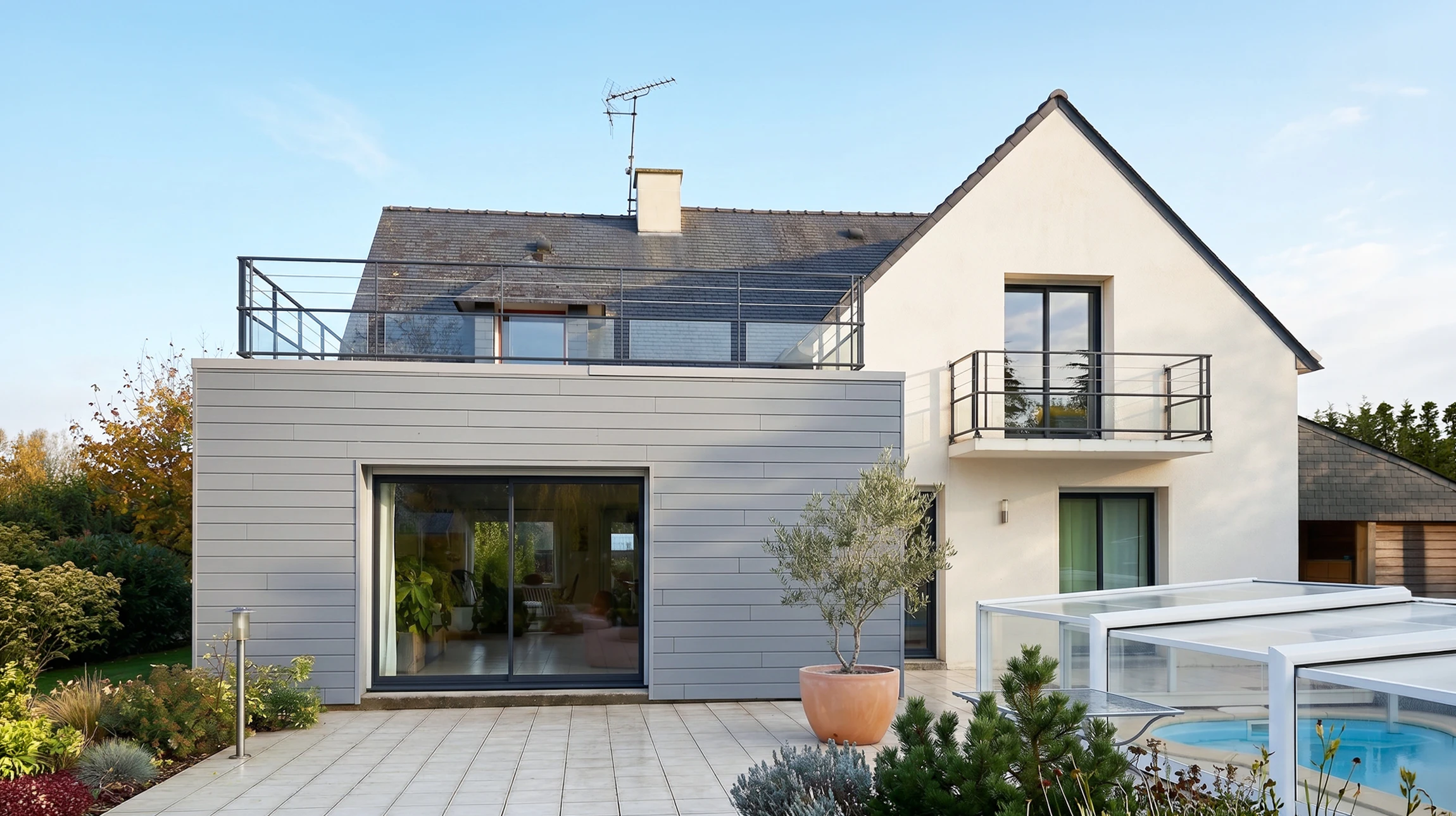 Façade extérieure d'une maison traditionnelle avec bardage bois vertical grisé et soubassement en pierre naturelle